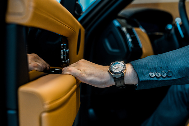 image recadrée de l'homme d'affaires avec porte de fermeture montre de luxe tout en étant assis dans la voiture
 - Photo, image