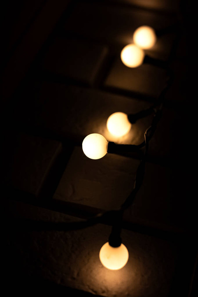Bright bulbs of a garland on a brick wall background close up - Photo, image