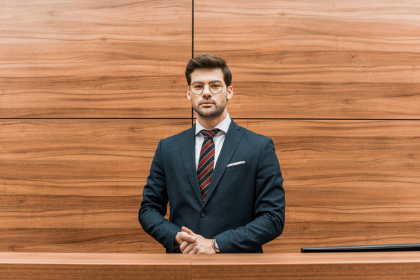 handsome businessman in eyeglasses standing at reception of modern office  - Fotografie, Obrázek