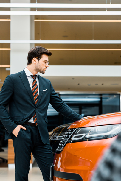 side view of handsome businessman in eyeglasses choosing car in dealership salon - Fotó, kép