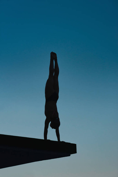 Handstand sukeltaja aluksella valmistautuu hyppäämään hämärässä
 - Valokuva, kuva