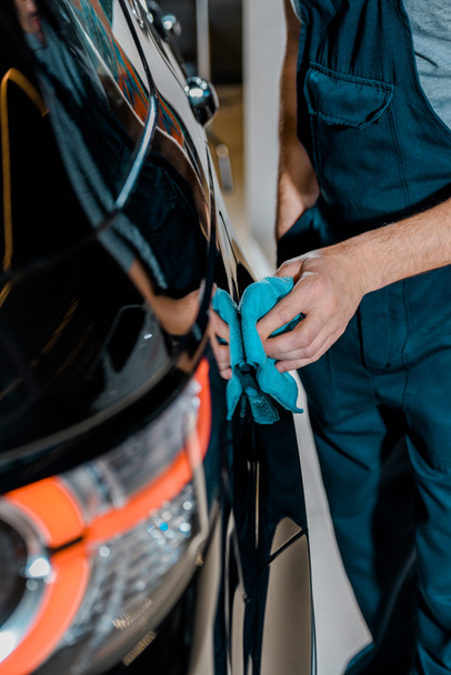 partial view of auto mechanic cleaning car with rag at auto repair shop - Φωτογραφία, εικόνα