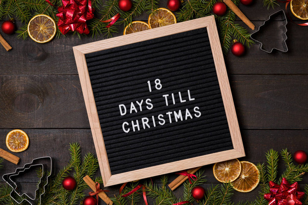 18 ημέρες μέχρι την αντίστροφη μέτρηση Χριστούγεννα αισθάνθηκε flatlay Διοικητικό Συμβούλιο επιστολή στον σκοτεινό ρουστίκ ξύλο, τραπέζι με Χριστουγεννιάτικη διακόσμηση και έλατα οικότροφος δέντρο - Φωτογραφία, εικόνα