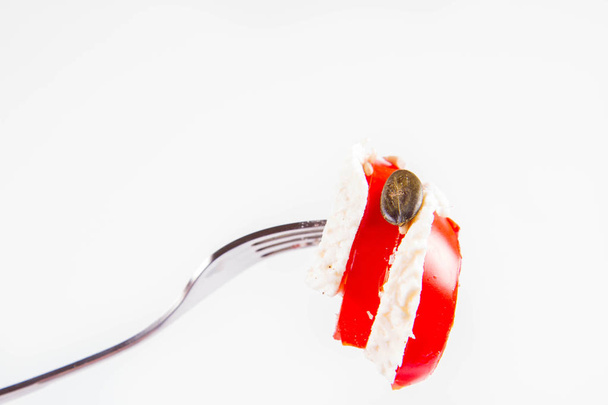 Caprese salad - tomato with mozzarella on a fork on a white background - Фото, изображение