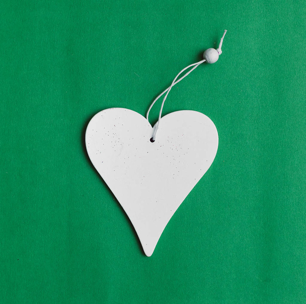 White heart shape toy with copy space isolated on green background. - Foto, imagen