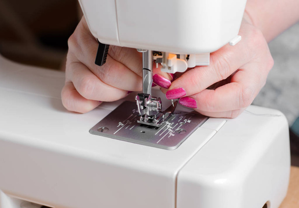 A seamstress puts the needle in the sewing machine. Close up - Foto, Bild