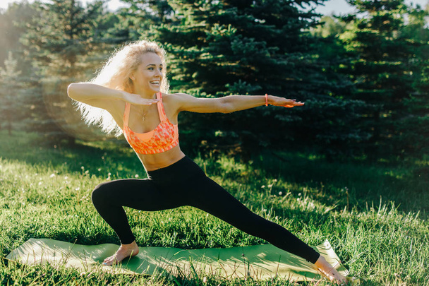 Image of young curly-haired sports woman practicing yoga on rug  - Фото, зображення