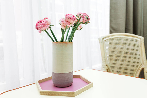 Różowe kwiaty w wazonie liliowy przeciwko białe okno. W wazonie na stole bukiet Aster. - Zdjęcie, obraz