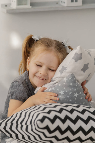 Маленькая красивая девочка с легкими подушками в уютной комнате
. - Фото, изображение