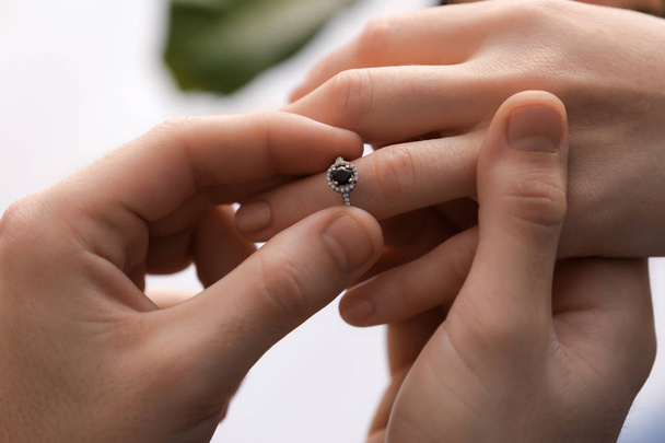 Jovem colocando anel de noivado no dedo da noiva, close-up
 - Foto, Imagem