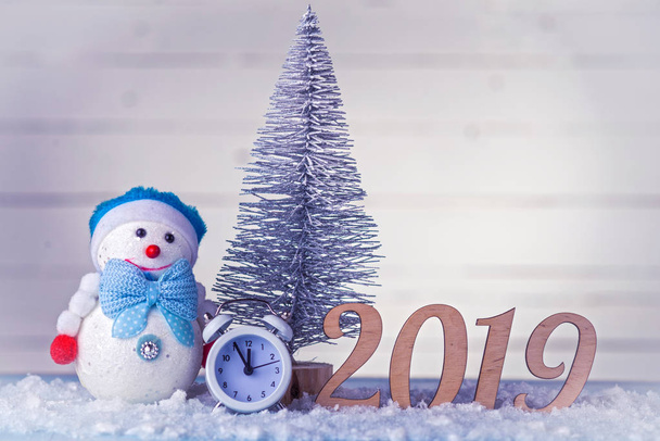 新年の組成: 時計、雪だるま、碑文 2019 および木製の背景上にクリスマス ツリー。コピー スペース クリスマス背景. - 写真・画像