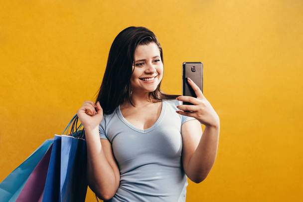 Woman shopping with a smart phone and carrying bags - Foto, immagini