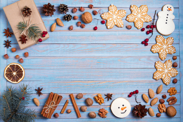 Christmas gingerbread cookies, gift box, nuts and spices on blue wooden background with copy space for text. Holiday, celebration, festive and cooking concept. New Year and Christmas composition, postcard - Photo, Image