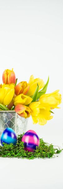 A bouquet of tulips, in front two striped Easter eggs in moss, vertical banner - Foto, Bild