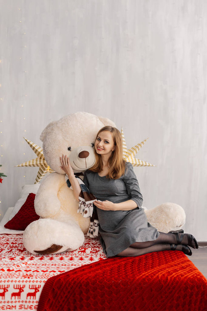 Very beautiful girl on the bed with a bear in the Christmas room. - Fotografie, Obrázek