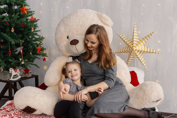 Very beautiful girl and her baby on the bed with a bear in the Christmas room. - Foto, immagini