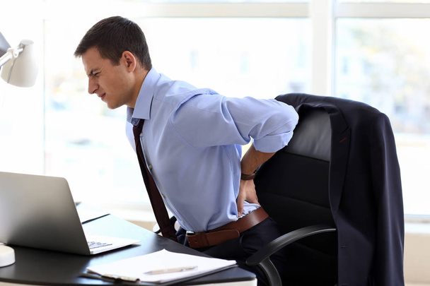 Jonge zakenman die lijden aan rugpijn in kantoor - Foto, afbeelding