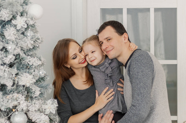 Щаслива і красива сім'я з трьох у святковій світлій новорічній кімнаті
. - Фото, зображення