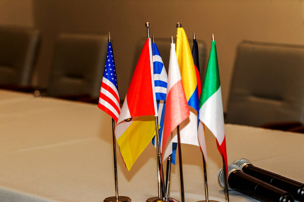 Many colorful national flags in a conference room - Business and communication vehicle concept. European pennants on the table of the conference hall according to the countries of the meeting - Photo, Image