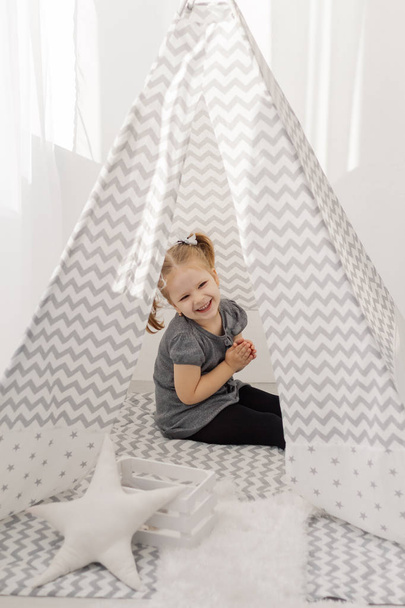A girl plays in a tepee with toys. - Photo, image