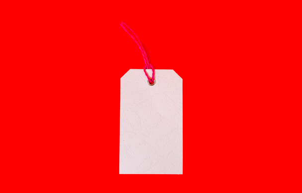 White price tag on red background. Plain price tag.  - Photo, Image