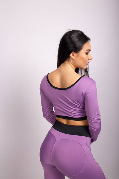 Sport woman in sport style clothes. Attractive and sportive woman in purple leggings  - Fotó, kép