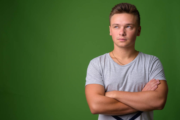 Studio shot of young handsome man against green background - Photo, Image