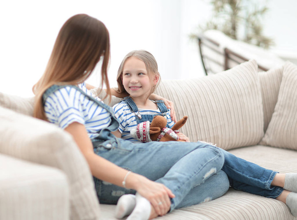 mom and little daughter sitting on the couch in a cozy living room - Foto, Imagen