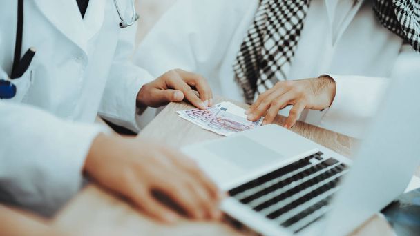 Close Up Arabic Patient Giving Money to Doctor. Corruption Concept. Man Giving Dollars To Doctor. Payment. Salary Time. Reception of Therapist. Discussing Diagnosis. Examination. Medical Concept. - Foto, Imagem