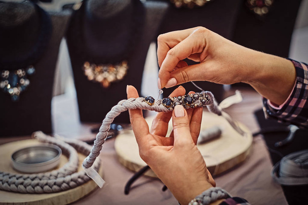 Nahaufnahme einer Frauenhände, die handgefertigte Halsketten herstellt - Foto, Bild