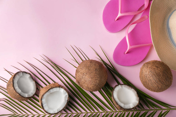 Rijpe kokosnoten, strand-hoed en slippers op kleur achtergrond - Foto, afbeelding