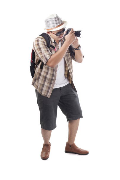 Traveling people concept.Portrait of Asian male backpacker photographer tourist isolated on white. Full body portrait. Taking Pictures with his mirrorrless - Фото, изображение