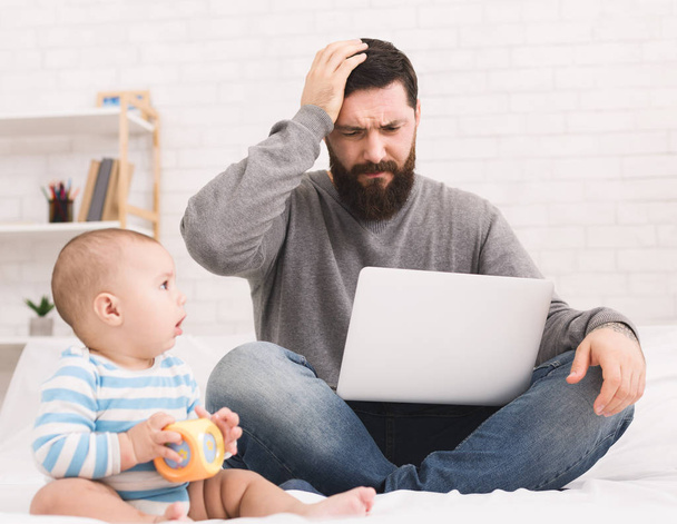Stressed dad trying to work and watching for baby - Photo, Image