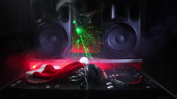 Mezclador de DJ con auriculares en el fondo oscuro club nocturno con árbol de Navidad Nochevieja. Vista de cerca de los elementos de Año Nuevo en una mesa Dj. Concepto de fiesta festiva. Espacio vacío
 - Metraje, vídeo