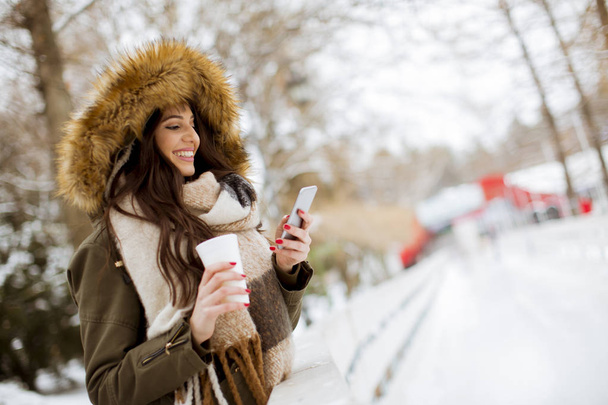 Портрет молодой женщины в снежном парке пьет чай
 - Фото, изображение