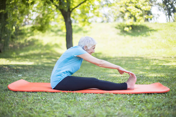 Panie starszy, zwiększenie elastyczności ciała przez rozciąganie w parku - Zdjęcie, obraz