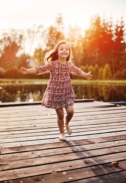 Cheerful and littlel girl realxing on a jetty - Foto, Imagem