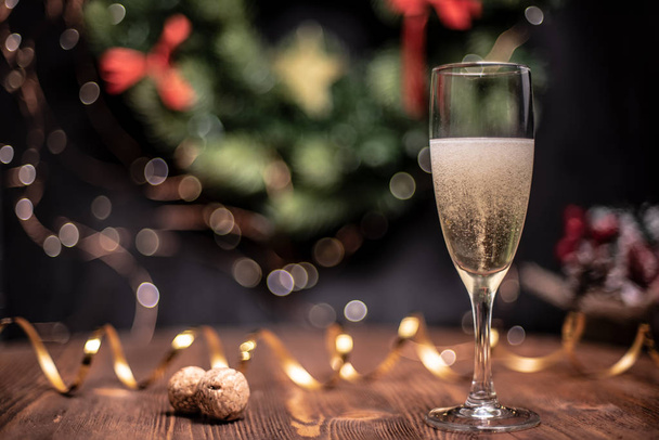 Vlotte schaduwrijke Kerstmis en Nieuwjaar decoratie achtergrond met ronde bokeh, gouden lint en glas champagne en kurk - Foto, afbeelding