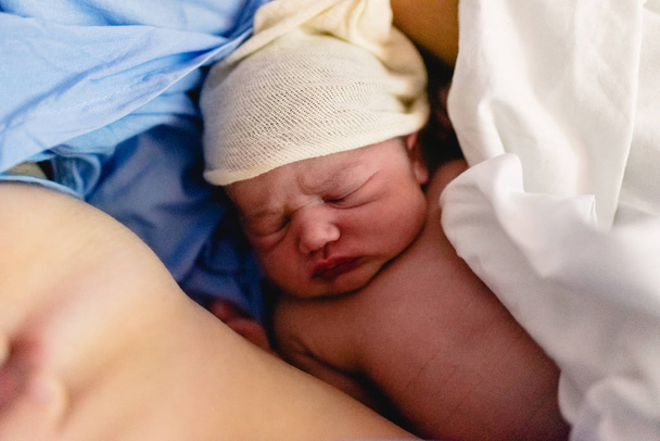 Νεογέννητο μωρό στο στήθος της μητέρας του στο νοσοκομείο. - Φωτογραφία, εικόνα