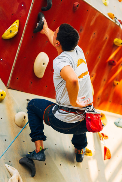 Young sporty man is bouldering in a climbing hall - 写真・画像