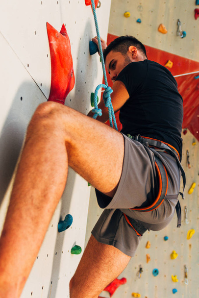 Hombre escalador en pared de escalada artificial en el gimnasio de bouldering - Foto, imagen