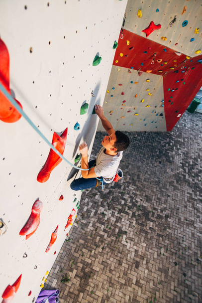 Giovane uomo si arrampica su una parete di roccia all'aperto - Foto, immagini
