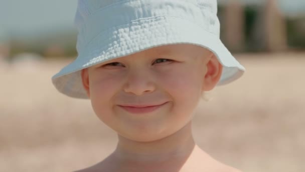 Nahaufnahme Porträt eines lächelnden europäischen kleinen Jungen mit weißem Hut, der viel Spaß im Freien hat - Filmmaterial, Video