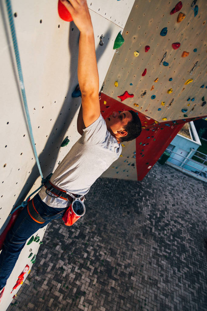 Sportlicher junger Mann bouldert in einer Kletterhalle - Foto, Bild