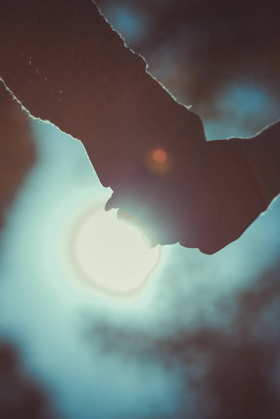 Закохана пара ходить в осінньому парку, тримаючись за руки і дивлячись на сонячне світло
 - Фото, зображення