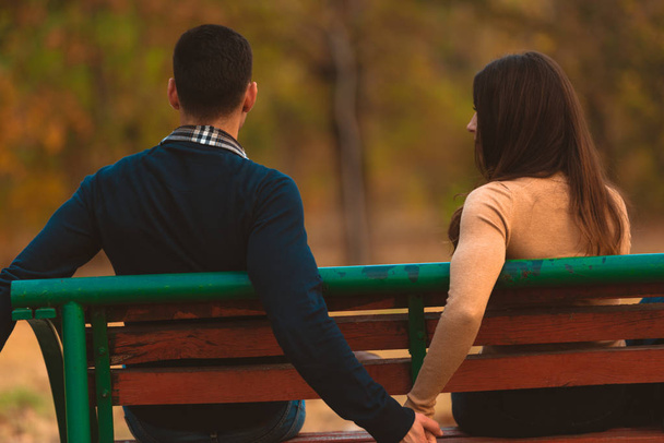 glückliches Paar, das auf einer Bank sitzt und glückliche Momente am herbstlichen Mittag teilt. - Foto, Bild