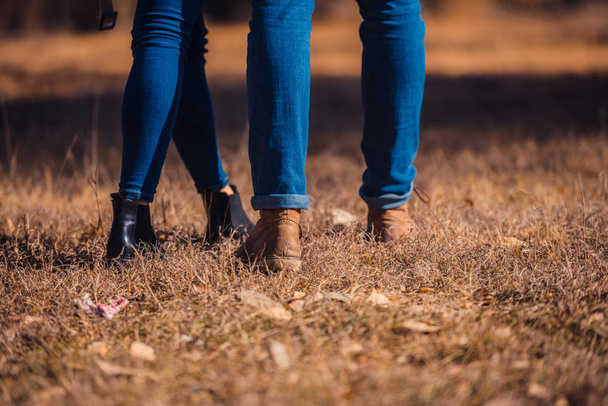 Süßes Paar in Jeans steht im Gras im Park, auf den Herbstblättern - Foto, Bild
