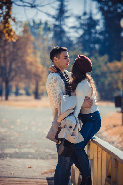 Amoristinen pari halailee puistossa sillalla ja nauttii kauniista syyspäivästä.
 - Valokuva, kuva