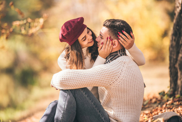 Wonderful couple is looking happy while looking at each other in autumn park - Photo, Image