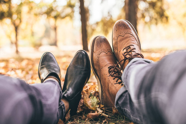 Пара отдыхает в парке, показывает свои ботинки
 - Фото, изображение